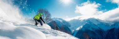 Kar yamacındaki bir snowboardcunun dinamik görüntüsü. Parlak renkler, canlı detaylar, kış sporları reklamı için uygun. Geniş pankart biçimi.