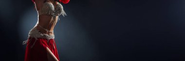 Fotokopi alanı olan kırmızı kostümlü bir dansçının sanatsal çekimi. Zarafet ve hareketin altını çizmek, moda veya dans promosyonları için mükemmel. Koyu arkaplan.