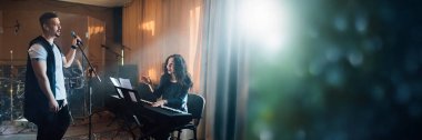 Sıcak ışıklandırması olan bir stüdyoda iki müzisyen. Müziğe odaklı projeler için ideal. Sağ tarafında kopyalama alanı olan geniş bir pankart olarak kullan.