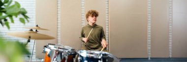 Genç bir baterist modern bir stüdyoda davul çalıyor. Tarafsız tonlar çağdaş bir titreşim yaratır. Müzikle ilgili promosyonlar ya da yaratıcı projeler için mükemmel. Kopyalama alanı olan geniş pankart.