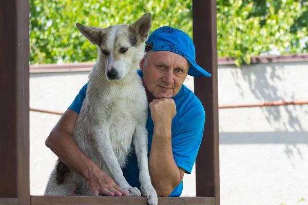 美丽的白种人成熟男子和他可爱的年轻白狗站在夏日阳台上的户外肖像 — 图库照片