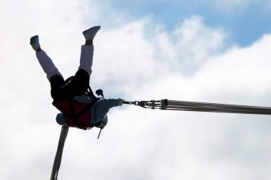 Woman makes selfie in mid-air, hanging on bungee ropes