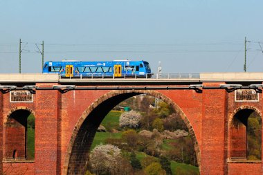 Netzschkau, Almanya - 30 Nisan 2023: Vogtland bölgesel treni Almanya 'nın Saksonya kentindeki dünyanın en büyük tuğla inşa edilmiş demiryolu köprüsü olan Goltzsch Viaduct' u geçiyor