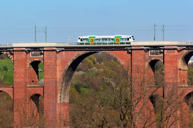 Netzschkau, Almanya - 30 Nisan 2023: Vogtland bölgesel treni Almanya 'nın Saksonya kentindeki dünyanın en büyük tuğla inşa edilmiş demiryolu köprüsü olan Goltzsch Viaduct' u geçiyor.