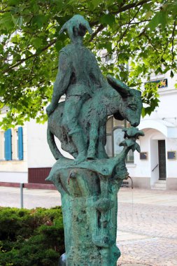 Werdau, Almanya - 5 Haziran 2023: Eşeğe ters oturan bir soytarı heykeli ile sokak çeşmesi