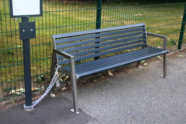 Otobüs durağındaki metal bank, hırsızlık ve vandalizmi önlemek için zincirli bir direğe bağlı.