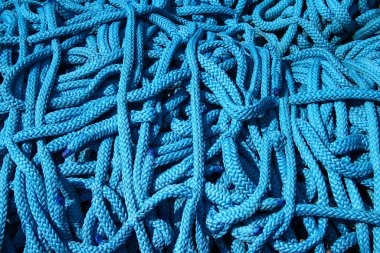 Parlak mavi bir halat yığınının birbirine dolanmış halatı, karmaşık örgülü dokusunu ve canlı kolosunu gözler önüne seriyor.