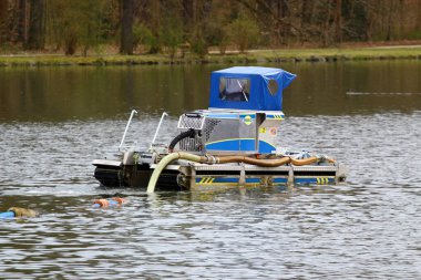 Greiz, Almanya - 27 Mart 2024: Su yüzeyindeki göl ve gölleri temizleyen ve derinleştiren yüzen eşeleyici