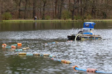 Greiz, Almanya - 27 Mart 2024: Su yüzeyinde verimli bir şekilde çalışan, gölet ve gölleri temizlemek ve derinleştirmek için tasarlanmış küçük yüzen bir süzgeç