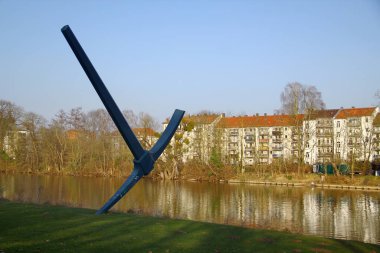 Kassel, Almanya - 10 Mart 2025: Kazma, Claes Oldenburg 'un Fulda nehrindeki Hiroşima kıyısındaki çelik heykeli, 1982' de Documenta 7 'ye katkı.