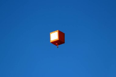 Açık mavi gökyüzünde yüzen kübik sıcak hava balonu