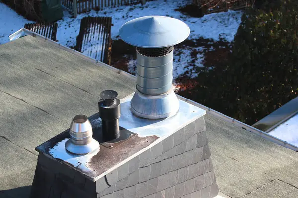 Modern metal baca bacaları, kış güneşinde tahta kaplı bir çatıda.