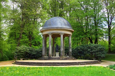 Huzurlu Tarihi Park 'ta Lush Green Trees tarafından çevrelenmiş bir heykeli olan Neoklasik Pavyon