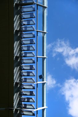 Mavi gökyüzüne karşı örgü yüzeyli metal merdivenlerin açılı görüntüsü