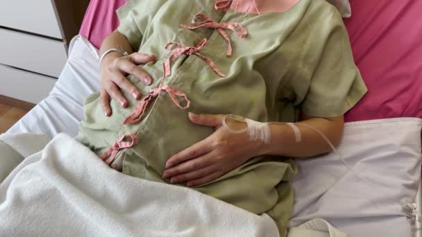 紧紧抓住孕妇的手 在医院的床上抚摸她的腹部 — 图库视频影像