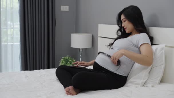 Těhotná Žena Pomocí Sluchátka Pro Své Dítě Poslech Hudby Posteli — Stock video