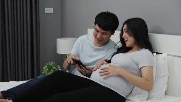 Zwanger Paar Met Smartphone Een Bed — Stockvideo