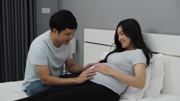 快乐的怀孕夫妇在床上爱抚宝宝 和宝宝在肚子里聊天 — 图库视频影像