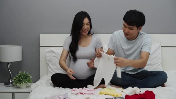 Έγκυο Ζευγάρι Προετοιμασία Βρεφικά Ρούχα Για Νεογέννητο Ένα Κρεβάτι — Αρχείο Βίντεο