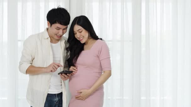 Έγκυος Ζευγάρι Που Χρησιμοποιεί Smartphone Φόντο Παραθύρου — Αρχείο Βίντεο