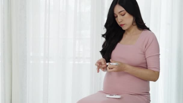 妊娠中の若い女性は血糖値計を持って家で自分で血糖値をチェックしています 妊娠糖尿病の概念は — ストック動画