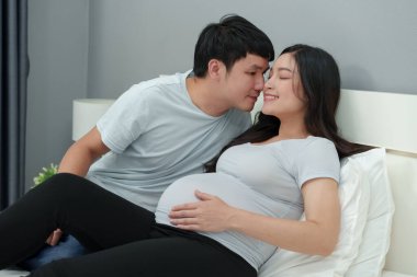 Koca hamile karısını öpüyor ve mutlu oluyor.