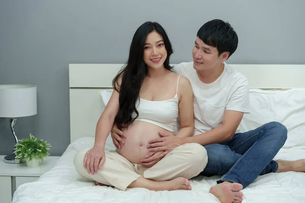 这对已婚夫妇怀孕了 男人把他怀孕的妻子抱在床上 — 图库照片