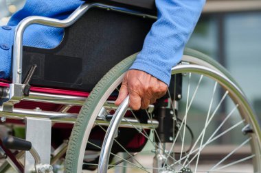 close up hand of disabled senior woman on the wheel of a wheelchair