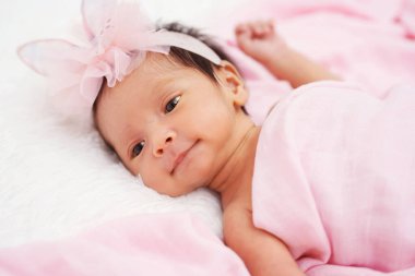 happy newborn baby girl in blanket on a bed