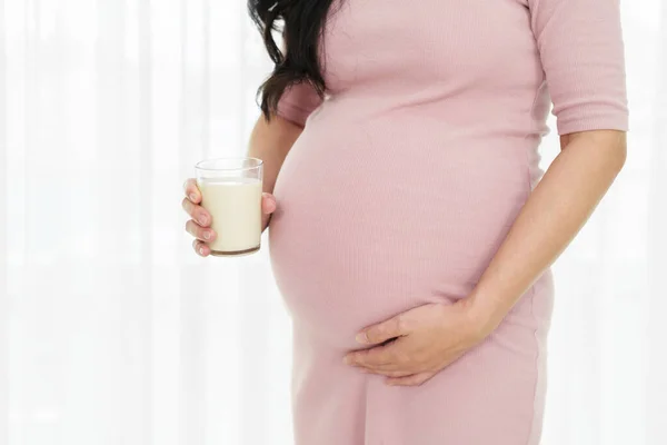 close up pregnant woman drinking a milk at the window in bedroom