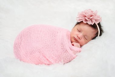 happy newborn baby girl sleeping in cloth wrap blanket on a bed	