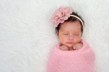 happy newborn baby girl sleeping in cloth wrap blanket on a bed	