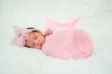 newborn baby girl sleeping in cloth wrap blanket on a bed