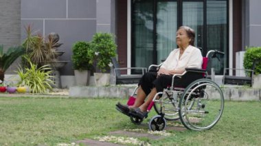 senior woman sitting in wheelchair at outside the house