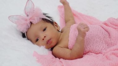 newborn baby girl in blanket on a bed