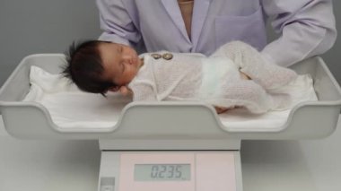 newborn baby weight measurement on the digital scales with doctor in hospital