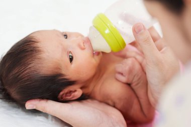 Anne yeni doğmuş bebeğini yatakta emziriyor.