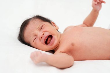 Yeni doğmuş bebek yatakta ağlıyor.