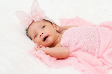 happy newborn baby girl in blanket on a bed