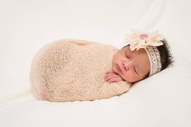 happy newborn baby girl sleeping in cloth wrap blanket on a bed	