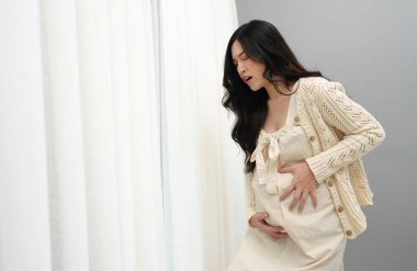 Hamile kadının arka planında karın ağrısı var.