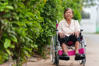 senior woman sitting in wheelchair at the park
