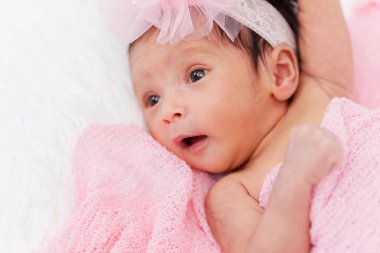 happy newborn baby girl in blanket on a bed
