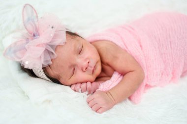 newborn baby girl sleeping in cloth wrap blanket on a bed