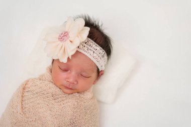 happy newborn baby girl sleeping in cloth wrap blanket on a bed	