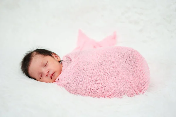 newborn baby sleep in cloth wrap blanket on a bed
