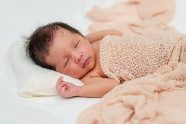 newborn baby sleeping in blanket on a bed