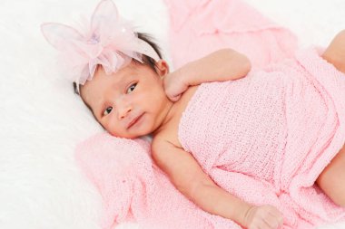 happy newborn baby girl in blanket on a bed