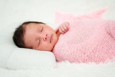 newborn baby sleep in cloth wrap blanket on a bed