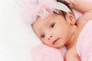 newborn baby girl in blanket on a bed